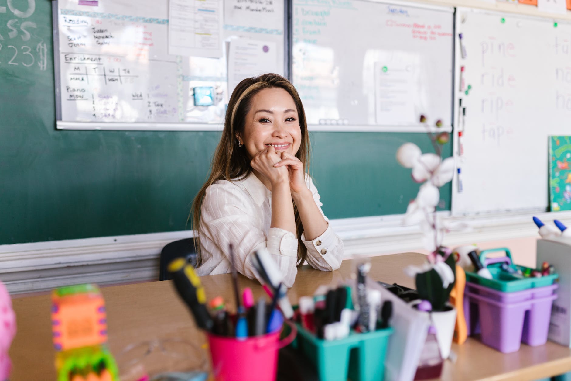 a woman sitting beside the blackboard smiling